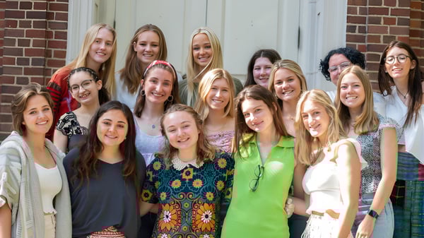 Un grupo de jóvenes alumnas sonríe frente a un edificio de ladrillo en el campus de la Chatham Hall School.