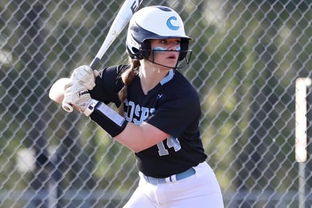 Un estudiante del Chesterfield School District está en uniforme de béisbol en el plato de bateo con un bate en la mano.
