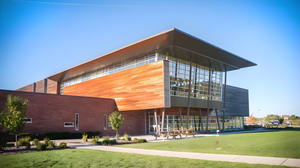El moderno edificio de Chicago Public Schools con fachada de ladrillo y vidrio en un terreno bien cuidado bajo un cielo despejado.