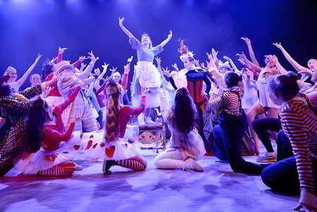 Un grupo de estudiantes del Chichester College presenta una obra de teatro colorida con iluminación dramática.