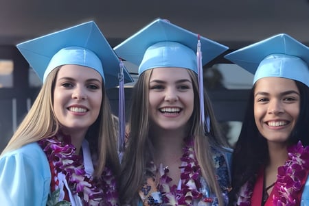 Tres estudiantes de la Chief Sealth High School posan juntas con ropa de graduación en una celebración.