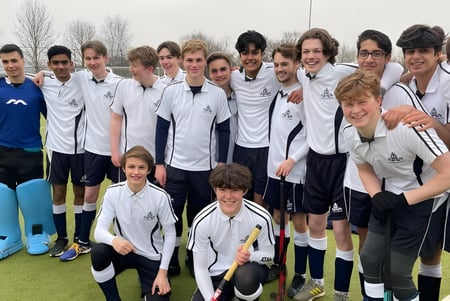 Un grupo de estudiantes de la Chigwell School posan en el campo de fútbol bajo un cielo nublado.