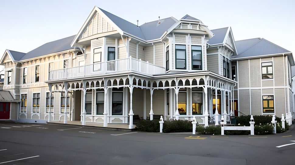 El edificio principal victoriano de la Chilton Saint James School con una veranda alrededor está rodeado de una calle y coches estacionados.