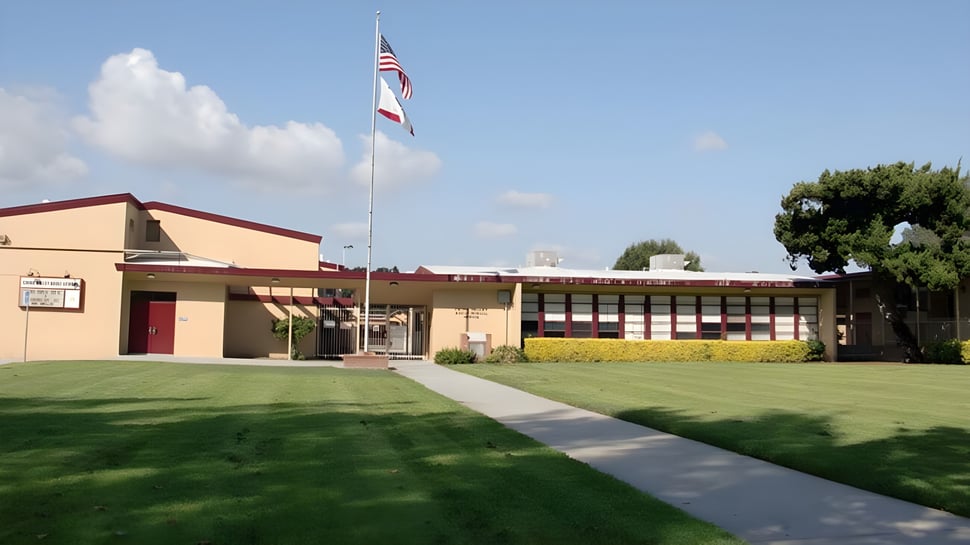 Un edificio de una sola planta con techo rojo y bandera americana en el terreno del Chino Valley Unified School District.