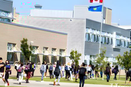 Un grupo de estudiantes camina por una pradera frente al moderno edificio de la Chinook High School.