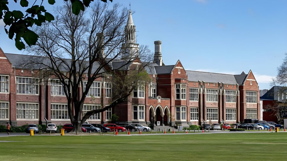 Un gran edificio de ladrillo decorado con una alta torre se encuentra en el terreno de Christchurch Boys High School.