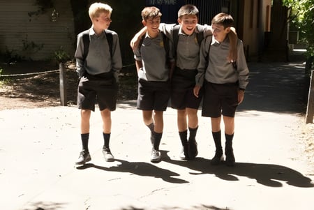 Un grupo de estudiantes está en el área exterior del campus de Christchurch Boys High School cerca de un camino de grava y arbustos.