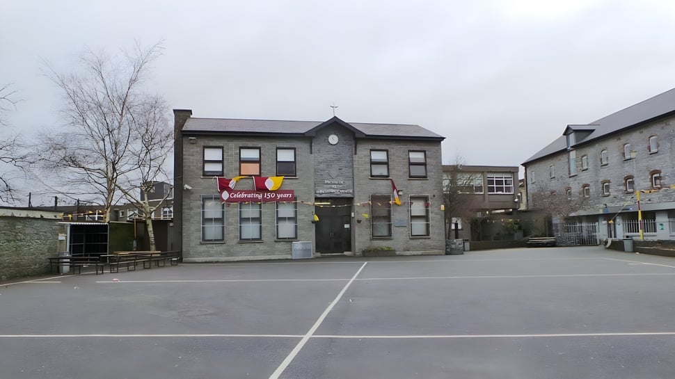 El edificio principal de la Christian Brothers School Kilkenny con varias ventanas y un patio pavimentado en primer plano.