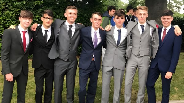 Un grupo de estudiantes en ropa formal está en el área verde del campus del Christ's College.