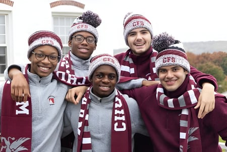 Un grupo de estudiantes de la Church Farm School lleva ropa de invierno uniforme y está frente a un edificio con columnas.