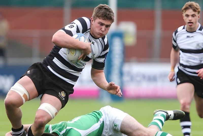 Un jugador de rugby del Cistercian College corre con el balón por el campo mientras otro jugador está en el suelo.