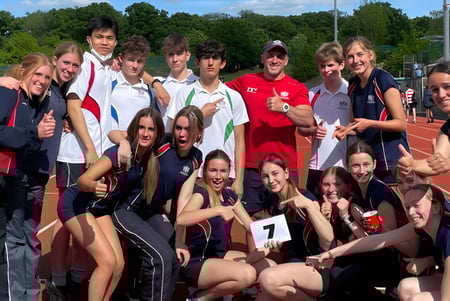 Un grupo de jóvenes atletas posan en el campo de deportes de la City of London Freemen’s School bajo un cielo azul.