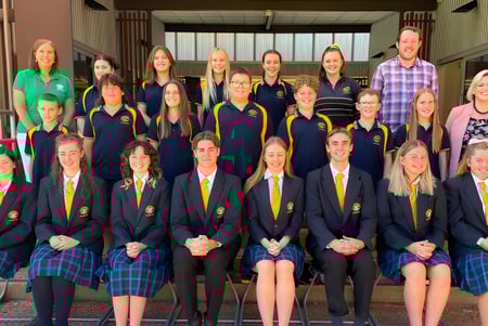 Un grupo de estudiantes de Clare High School está reunido frente a un edificio escolar.