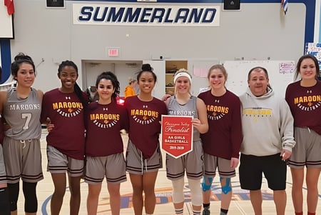 Estudiantes de la Clarence Fulton Secondary School están en uniformes deportivos juntos frente al cartel Summerland.