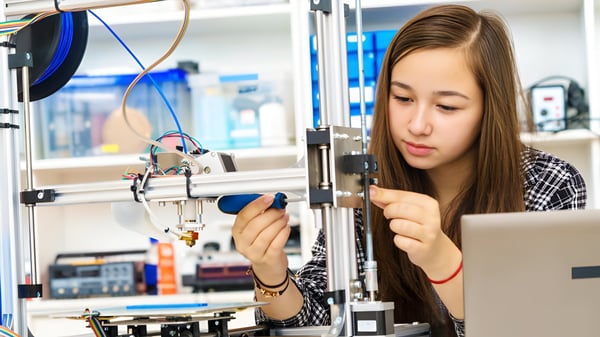 Una estudiante del Clarin College examina concentradamente una pieza en la impresora 3D.