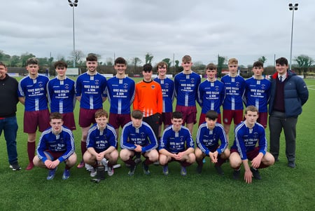 Un grupo de estudiantes del Clarin College posan en un campo de césped bajo un cielo nublado.