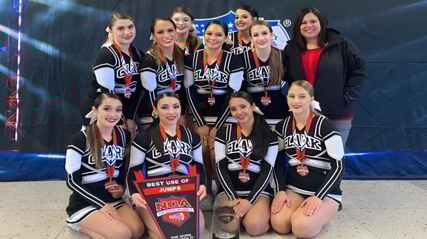 Un grupo de animadoras posan en uniformes a rayas blanco y negro en el escenario del Clark County School District.