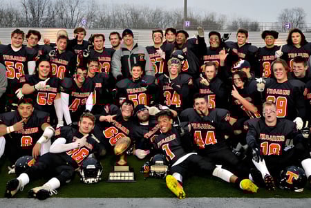 Un grupo de estudiantes de la Clarke Road Secondary School está reunido en un campo de hierba frente a árboles y edificios.