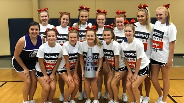 Un grupo de jóvenes animadoras en uniformes uniformes posan en el gimnasio de la Clarksville High School.