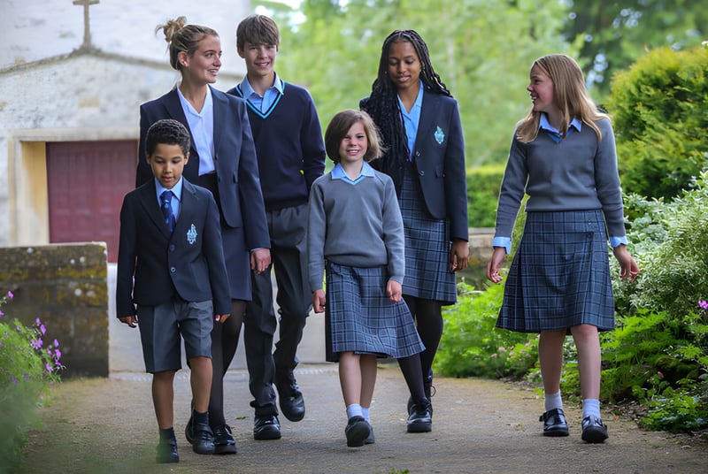 Estudiantes de la Clayesmore School caminan juntos por un camino a lo largo de amplias áreas verdes con un edificio al fondo.