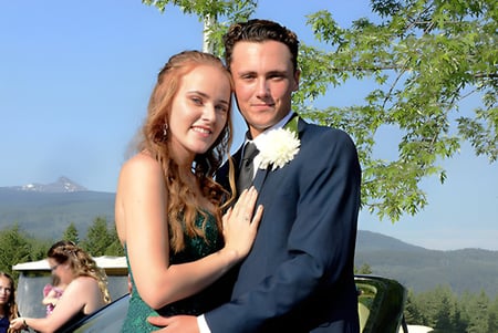 Una pareja se abraza frente a un paisaje montañoso en el terreno de la Clearwater Secondary School.