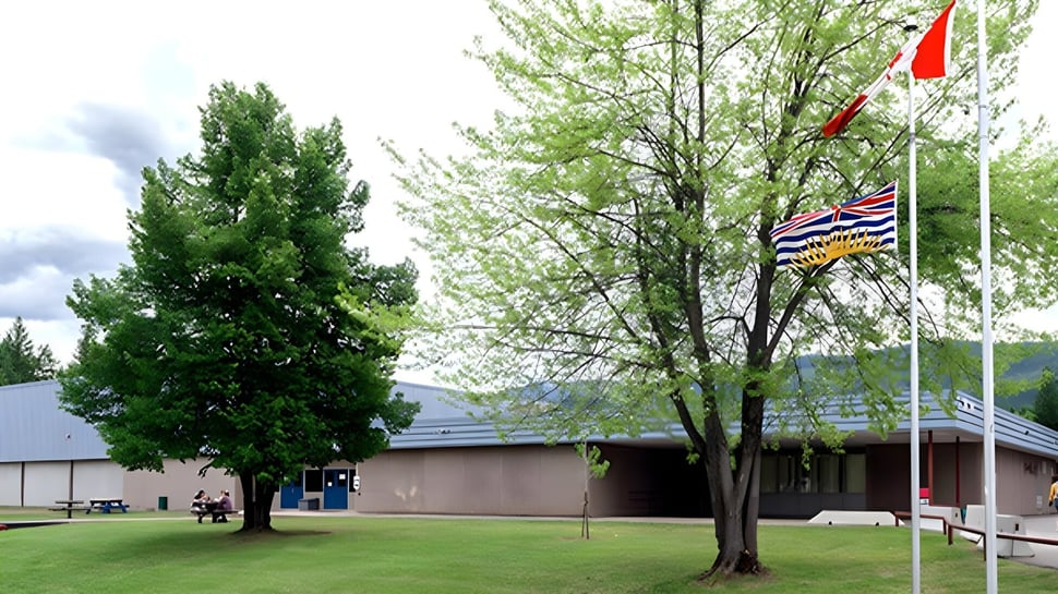 Área verde con varios árboles y un edificio al fondo en el campus de la Clearwater Secondary School.