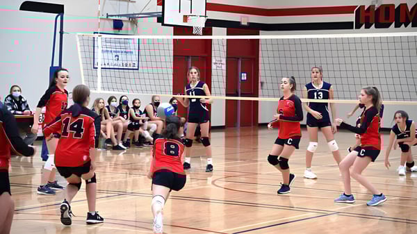 Estudiantes de la Clearwater Secondary School juegan al voleibol en una cancha de baloncesto con un tablero visible.