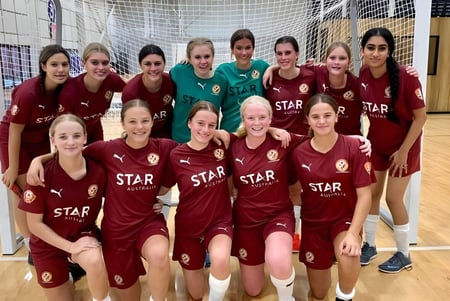 El equipo de fútbol de la Cleveland District State High School posa junto en el gimnasio con camisetas rojas y blancas con el logo de STAR.