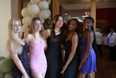 Un grupo de jóvenes mujeres posan con ropa formal frente a decoraciones en un evento de la Cobham Hall School.
