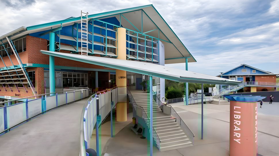 El moderno edificio con entrada y escaleras del Coffs Harbour Senior College bajo un cielo nublado.