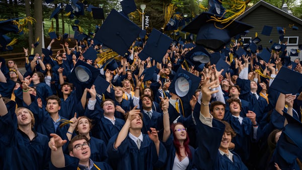 Graduados en togas azules celebran su graduación al aire libre en el campus de la Colaiste Chiarain Athlone.