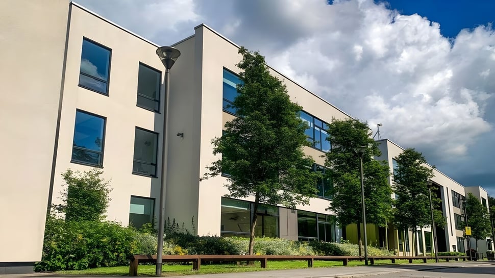 El moderno edificio de varios pisos con grandes ventanas de la Coláiste Choilm está rodeado de áreas verdes.