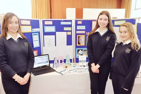 Tres alumnas en uniformes escolares están frente a un escaparate en el edificio escolar de Coláiste Mhuire Ballymote.
