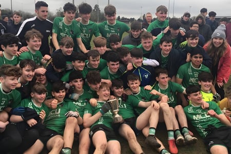 Un gran grupo de jóvenes futbolistas en camisetas verdes posan en el campo de fútbol de la Coláiste Mhuire Mullingar.