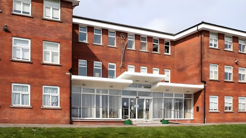 El edificio de ladrillo de varios pisos con entrada de vidrio en el terreno de la Colaiste Muire (Cobh).