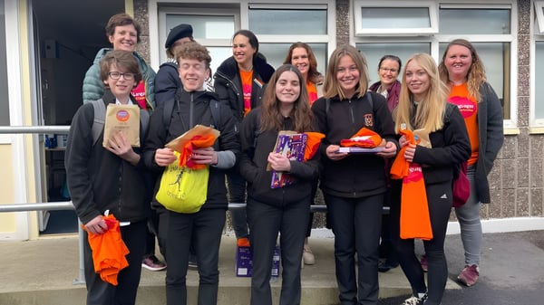Un grupo de estudiantes se encuentra frente a un edificio en el campus de la Colaiste Muire (Cobh) vestidos con ropa colorida.