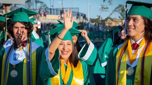 Un grupo de egresados en togas verdes y amarillas en el campus de la Coláiste Naomh Cormac.