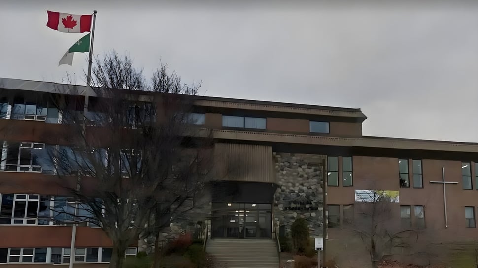 El edificio de varios pisos del Collège Notre-Dame con una bandera canadiense y una palestina en el techo bajo un cielo nublado.