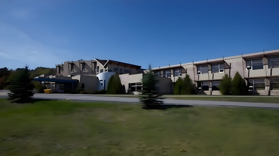 Vista del campus del Collège Sacré-Coeur con un campo de césped y modernos edificios de varios pisos bajo un cielo azul.