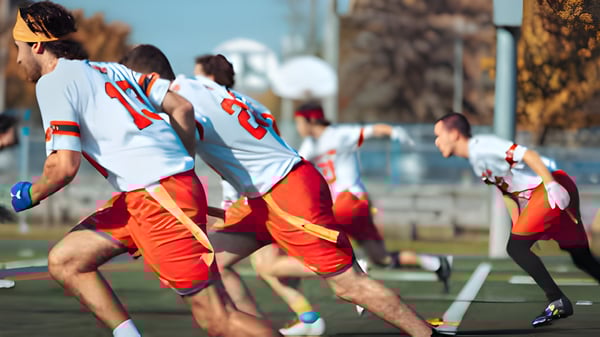 Un grupo de estudiantes del Collège Sainte-Anne juega un deporte de equipo en un campo deportivo en un entorno urbano.