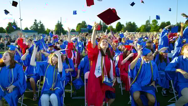 Los estudiantes del Collège Churchill High School celebran su fiesta de graduación al aire libre y lanzan sus birretes al aire.
