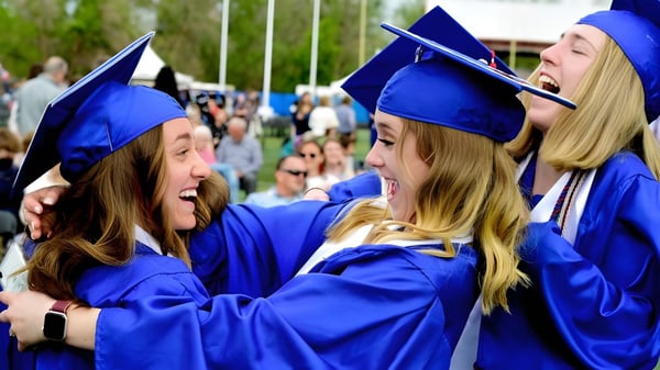 Dos estudiantes en togas de graduación azules se abrazan durante la ceremonia de graduación en la Colonel By Secondary School.