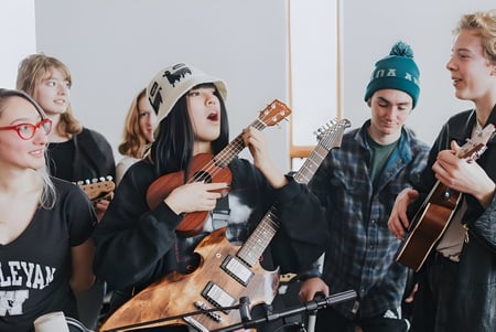 Estudiantes de la Colorado Rocky Mountain School se reúnen con instrumentos musicales en una sala.