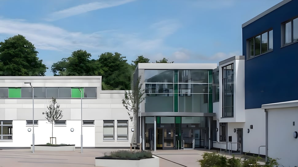 El moderno edificio de varios pisos con entrada de vidrio y acentos verdes en el campus del Comeragh College.