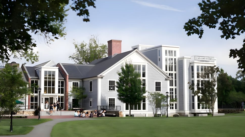 El edificio blanco de varios pisos de la Concord Academy está rodeado de árboles y un camino de piedra en un paisaje verde.