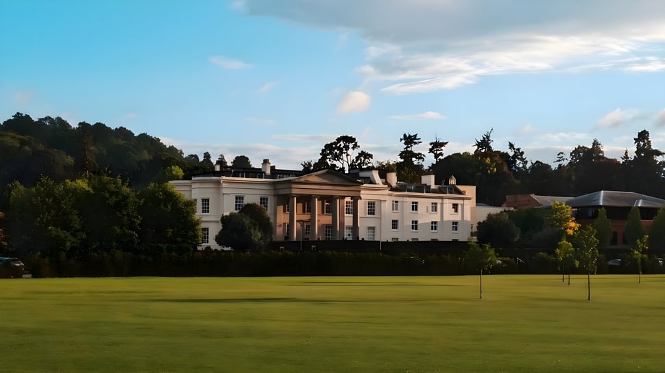 La gran casa blanca con un césped bien cuidado y árboles al fondo en el campus del Concord College.