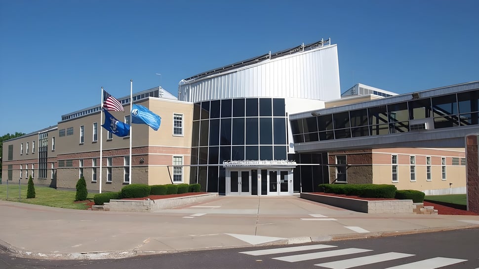 El moderno edificio principal de la Connecticut IB Academy con fachada de vidrio y área de entrada oficial.