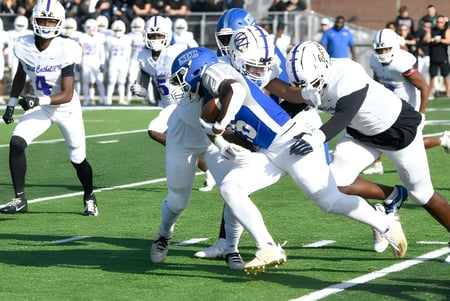 Un juego de fútbol americano con jugadores de la Conwell-Egan Catholic High School en camisetas blancas y azules se lleva a cabo en el campo.