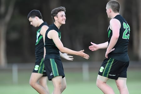 Dos estudiantes de la Corinda State High School se dan la mano en el campo de deportes.