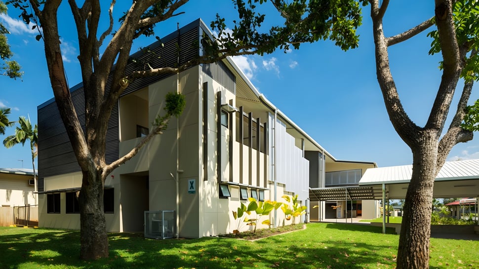 El edificio de varios pisos de la Cornafulla National School está rodeado de árboles y un césped verde.